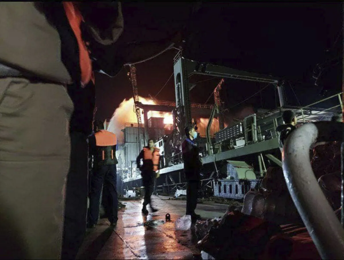 Personnel standing on Iran's navy support ship Kharg after having caught fire in the Gulf of Oman, on June 2, 2021. (Asriran.com via AP)
