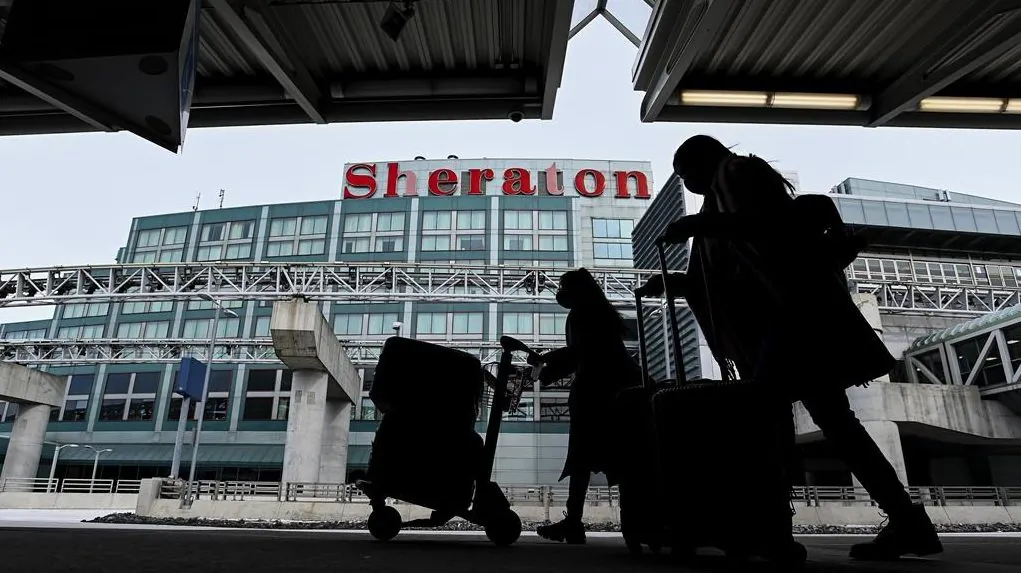 The airport hotel is shown as people walk outside with their luggage at Pearson International Airport during the COVID-19 pandemic in Toronto on Feb. 2, 2021. (The Canadian Press/Nathan Denette)