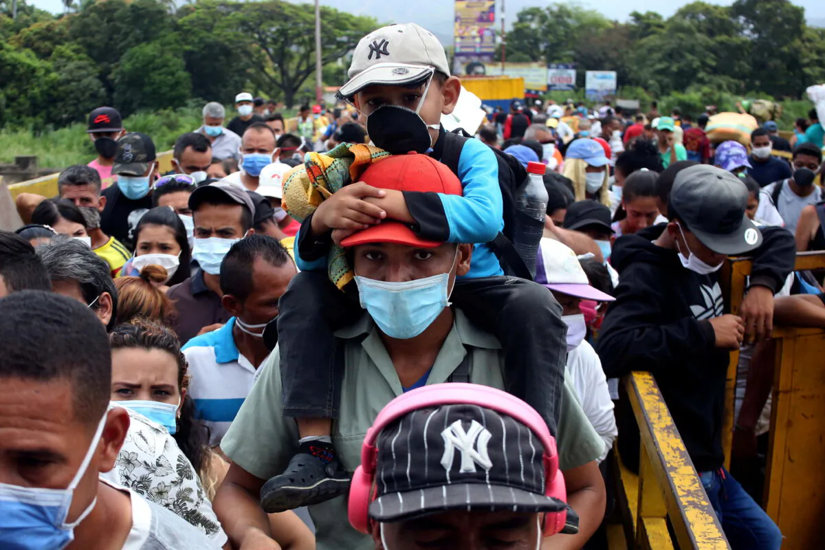 People wearing protective face masks line up to cross the border between Colombia and Venezuela at Simon Bolivar international bridge in Cucuta, Colombia on March 12, 2020. (REUTERS/Carlos Eduardo Ramirez/File Photo)