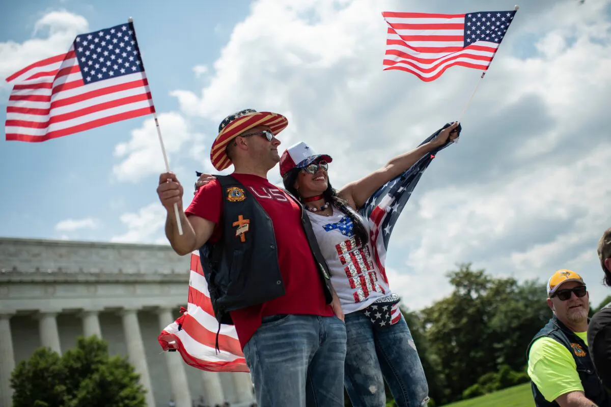 A couple waving U.S. flags looks on as bikers take part in the "Rolling Thunder" parade, part of the Memorial weekend honoring war veterans in Washington, on May 26 2019. (Eric Baradat /AFP via Getty Images)