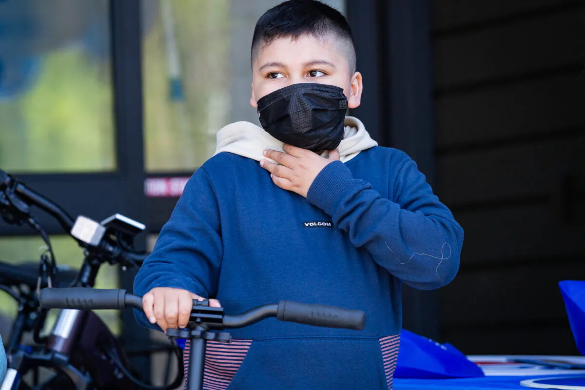 A child stands with his donated scooter at the Thompson Autism Center in Orange, Calif., on June 4, 2021. (John Fredricks/The Epoch Times)