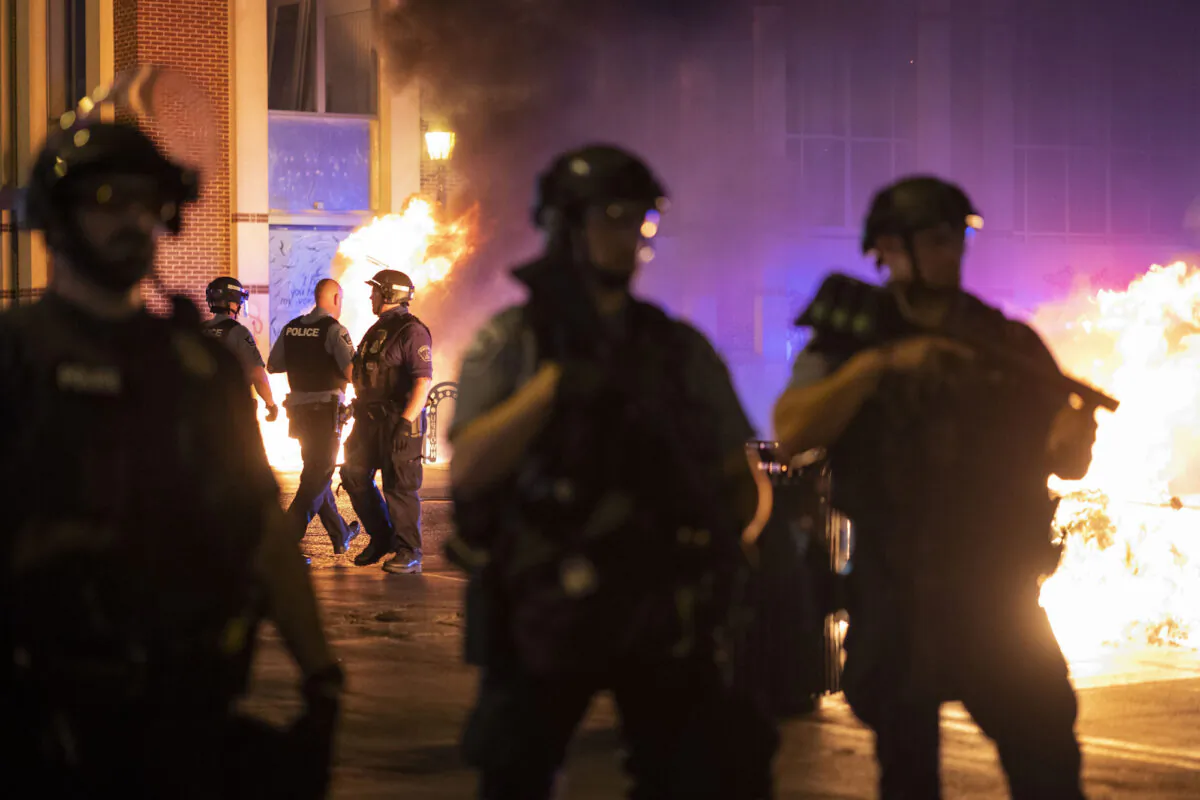 Police stand guard after protesters set fire to dumpsters in Minneapolis, Minn., on June 5, 2021. (Christian Monterrosa/AP Photo)