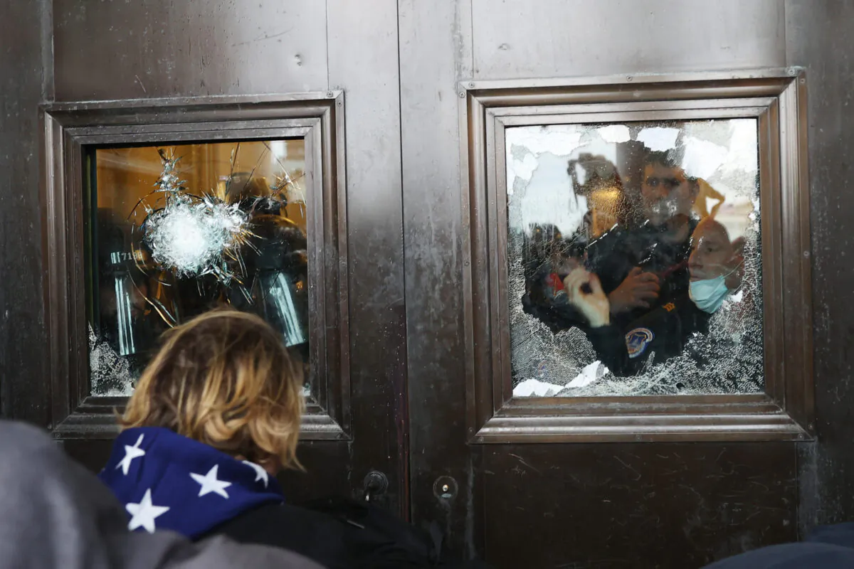 Capitol police officer looks out of a broken window as a crowd attempts to breach the U.S. Capitol, in Washington on Jan. 6, 2021. (Tasos Katopodis/Getty Images)
