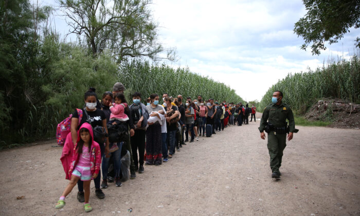 A group of Venezuelans waits to be picked up by Border Patrol after illegally crossing the Rio Grande from Mexico into Del Rio, Texas, on June 3, 2021. (Charlotte Cuthbertson/The Epoch Times)