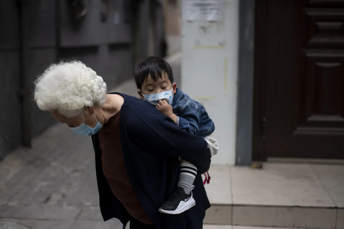 An elderly woman is piggybacking a boy along a street in Beijing, China on May 11, 2020. (Noel Celis/AFP via Getty Images)