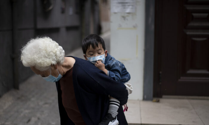 An elderly woman is piggybacking a boy along a street in Beijing, China on May 11, 2020. (Noel Celis/AFP via Getty Images)