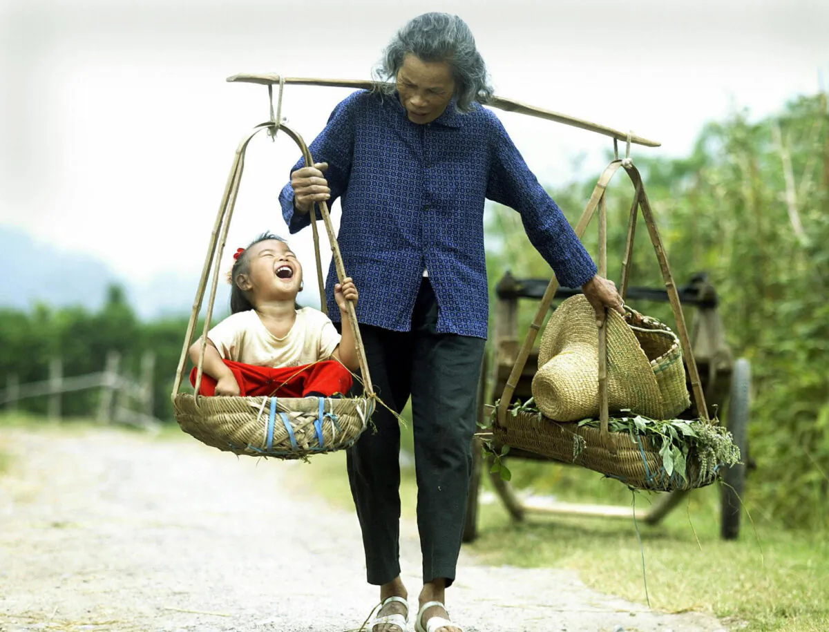 A grandmother carries her granddaughter outside the tourist mecca of Yangshuo, in southern China’s Guangxi Province, on Oct. 1, 2003. (Peter Parks/AFP via Getty Images)