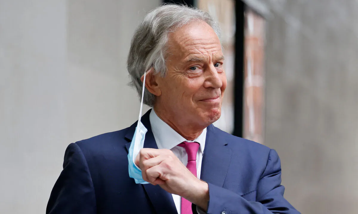 Former British Prime Minister Tony Blair removes his disposable face covering worn due to COVID-19, to pose for a photograph as he leaves the BBC in central London on June 6, 2021. (Tolga Akmen/AFP via Getty Images)