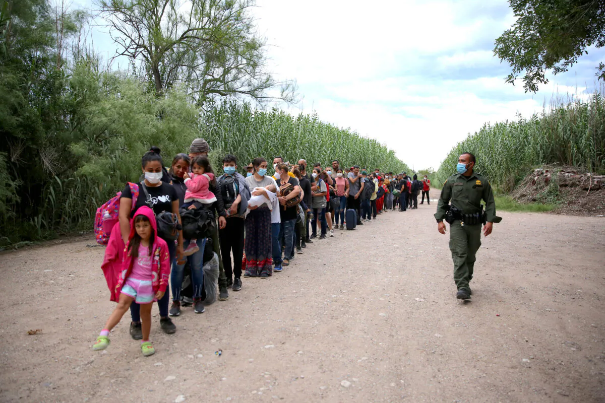 A group of Venezuelans wait to be picked up by Border Patrol after illegally crossing the Rio Grande from Mexico into Del Rio, Texas, on June 3, 2021. (Charlotte Cuthbertson/The Epoch Times)