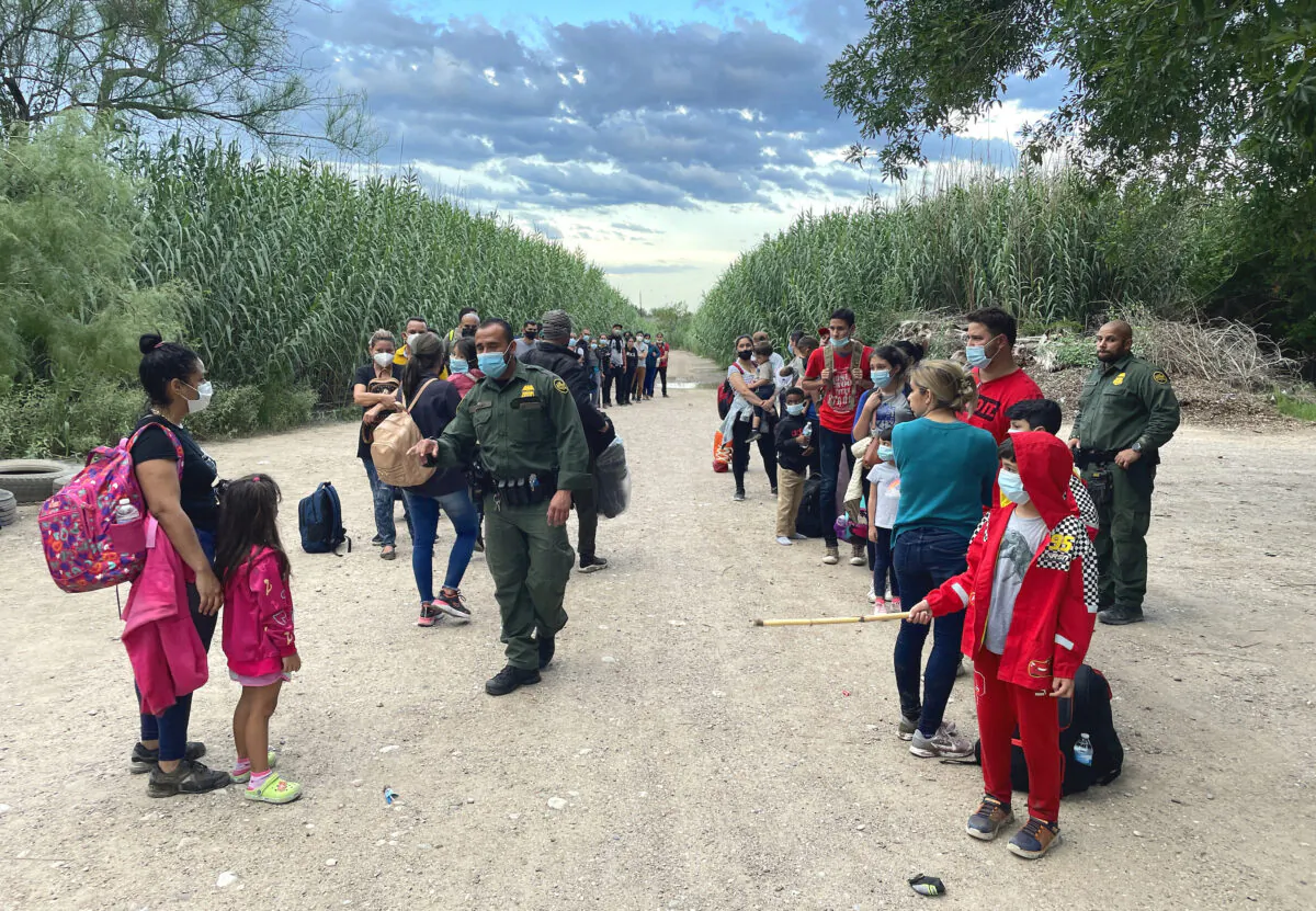 A group of Venezuelans wait to be picked up by Border Patrol after illegally crossing the Rio Grande from Mexico into Del Rio, Texas, on June 3, 2021. (Charlotte Cuthbertson/The Epoch Times)