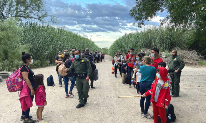 A group of Venezuelans wait to be picked up by Border Patrol after illegally crossing the Rio Grande from Mexico into Del Rio, Texas, on June 3, 2021. (Charlotte Cuthbertson/The Epoch Times)