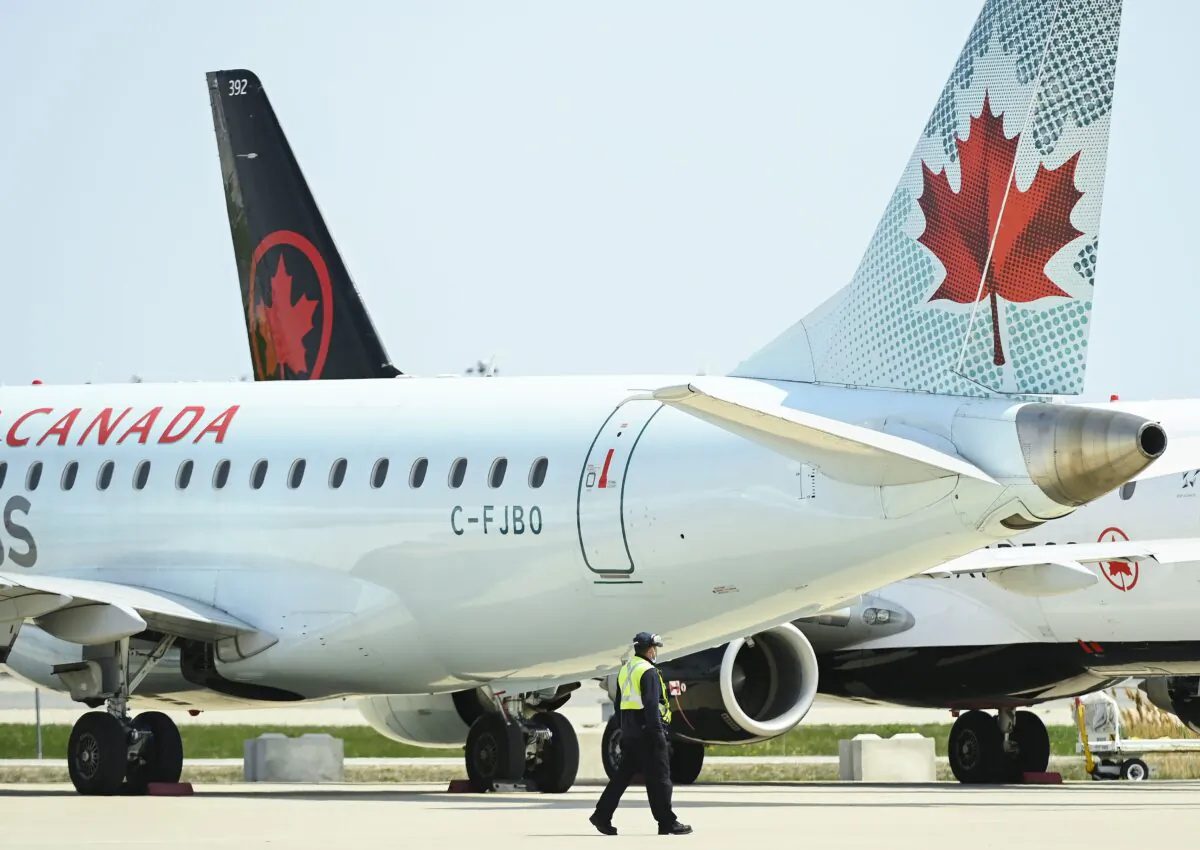 A worker walks past Air Canada planes grounded due to the pandemic on the tarmac at Pearson International Airport in Toronto on April 27, 2021. (The Canadian Press/Nathan Denette)