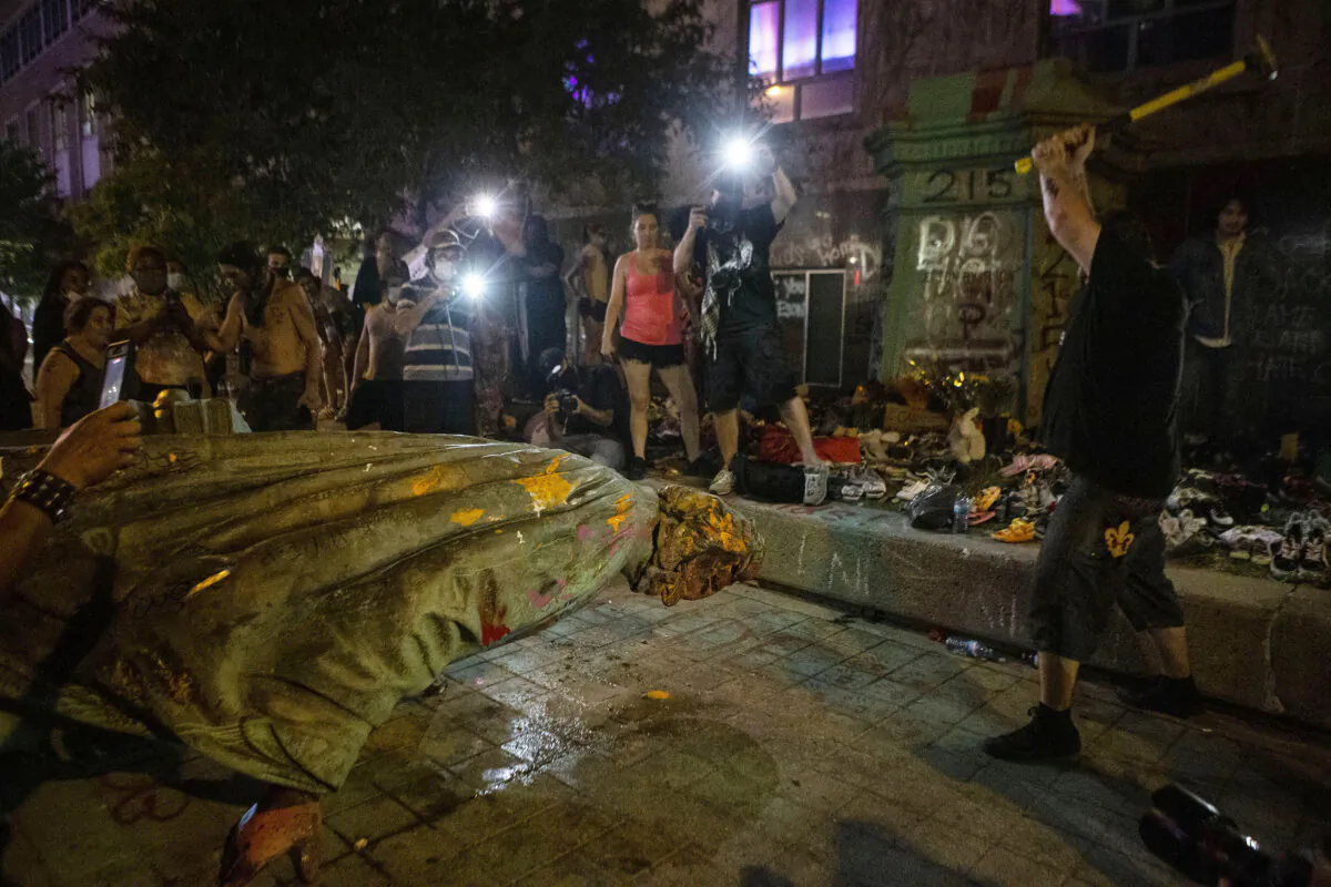 A protester swings a hammer in an attempt to remove the head of the just-toppled Egerton Ryerson statue in Toronto on June 6, 2021. (The Canadian Press/Chris Young)