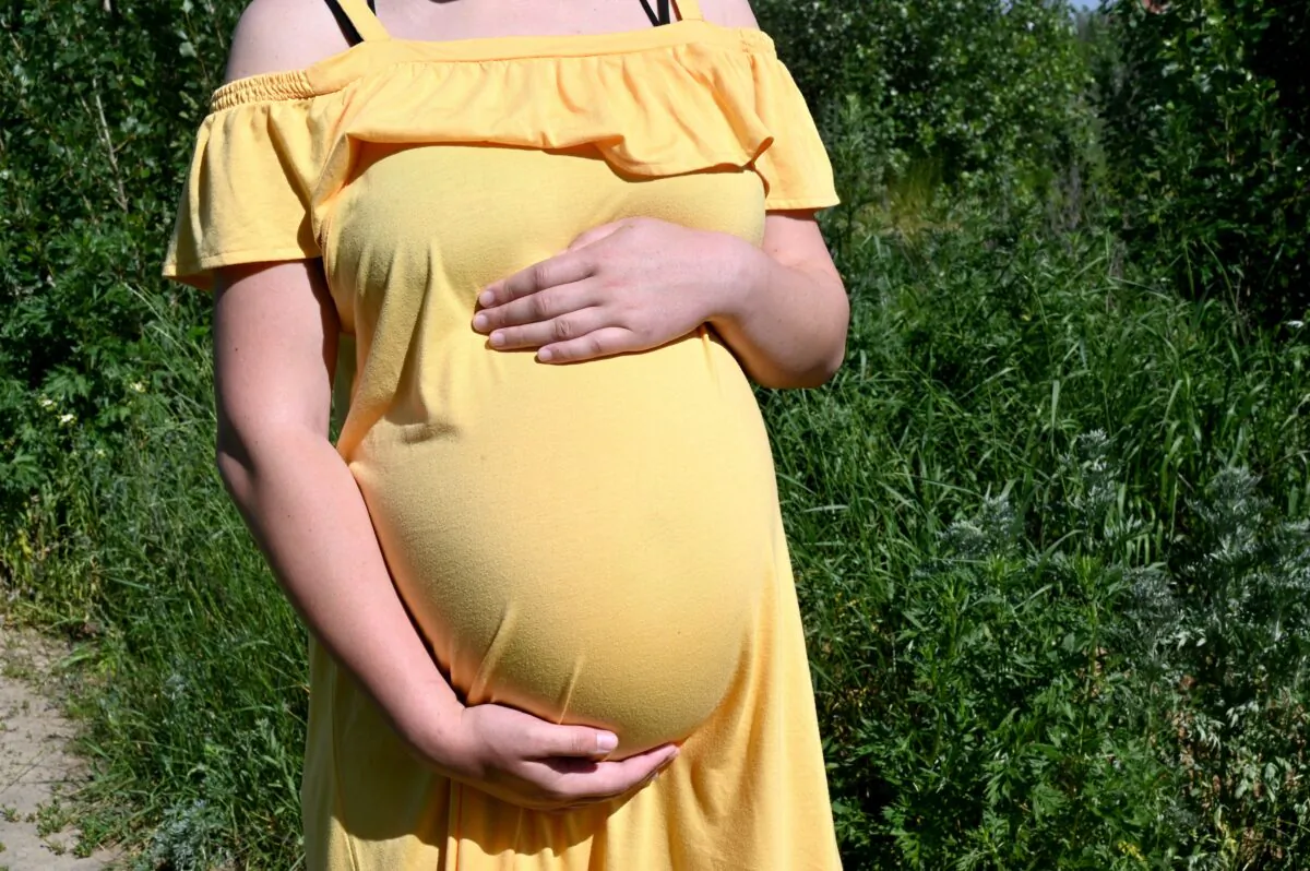 Olga, a 26-year-old going through her second surrogacy and expecting twins for a Chinese couple, holds her belly as she walks in the small town of Sophiya Borshchagivka, near Kiev on June 12, 2020. (Sergei Supinsky/AFP via Getty Images)