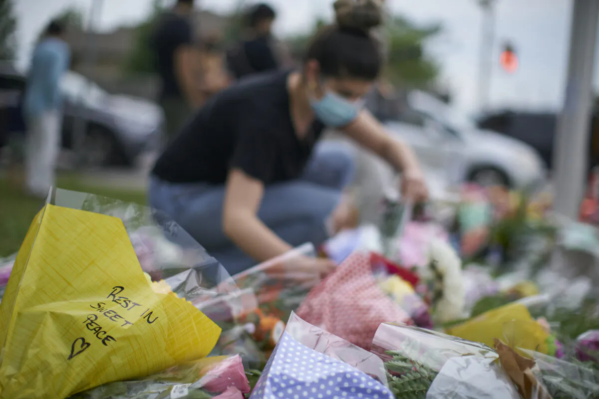 A woman arranges flowers at the scene of Sunday's hate-motivated vehicle attack in London, Ont. on June 8, 2021, in honour of the four members of a Muslim family that died and the youngest boy who is in hospital. (The Canadian Press/ Geoff Robins)