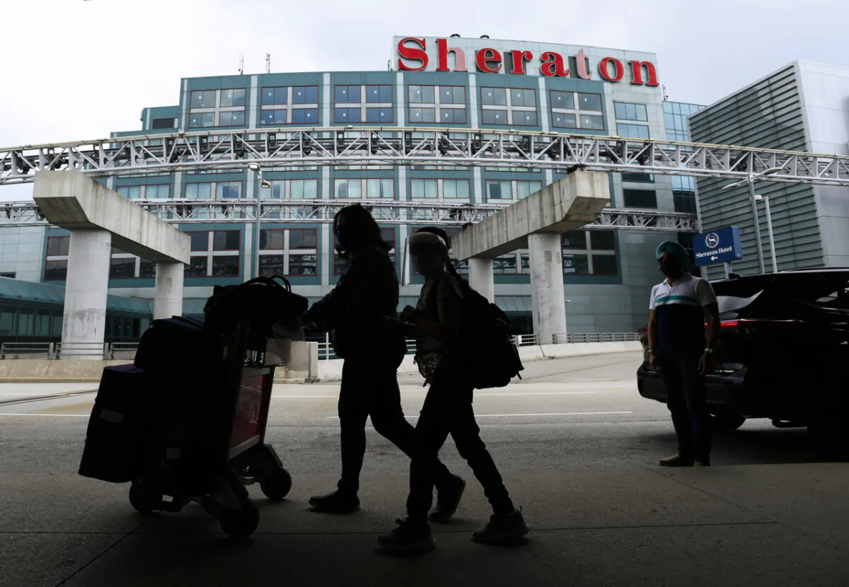 People walk with their luggage to travel to the United States during the COVID-19 pandemic in Toronto on June 9, 2021. The federal government says fully vaccinated Canadians and permanent residents crossing the border into Canada will soon no longer be required to stay at a hotel for part of their quarantine period. (The Canadian Press/Nathan Denette)