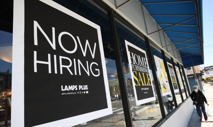 A pedestrian walks by a Now Hiring sign outside of a Lamps Plus store in San Francisco, Calif., on June 3, 2021. (Justin Sullivan/Getty Images)