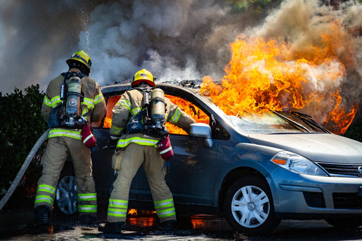Orange County Fire Authority firefighters extinguish flames from a car that ignited. A suspect said to be under the influence of drugs was taken into custody by Irvine Police Department officers in Irvine Calif., on June 11, 2021. (John Fredricks/The Epoch Times)