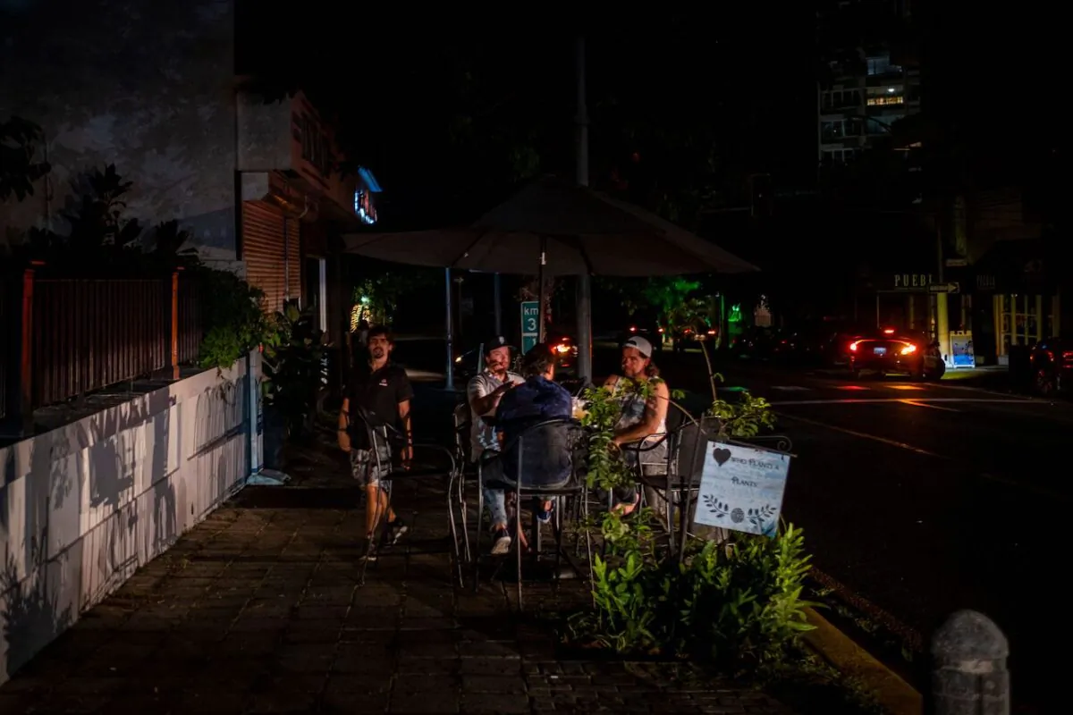 People are seen outside a restaurant on a dark usually busy street in San Juan, Puerto Rico, on June 10, 2021. (Ricardo Arguengo/AFP via Getty Images)