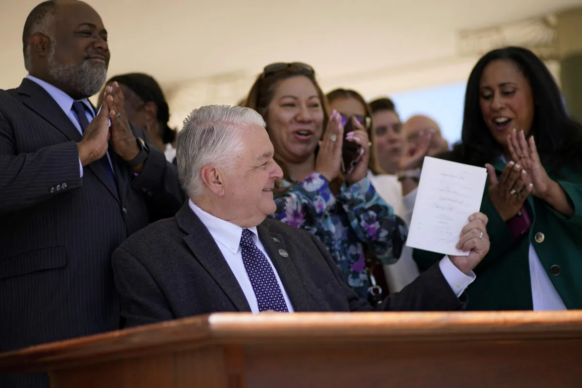 Nevada Gov. Steve Sisolak holds up a bill newly signed into law in Las Vegas, Nev., on June 11, 2021. (John Locher/AP Photo)