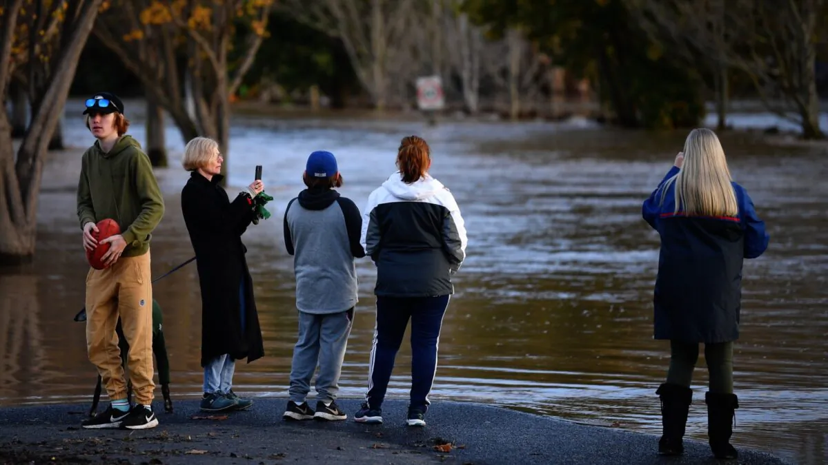 People are seen observing flood water in Traralgon, Victoria, Thursday, June 10, 2021. Thousands of Victorians have been left without power as wild winds and flooding hit the state. (AAP Image/James Ross)