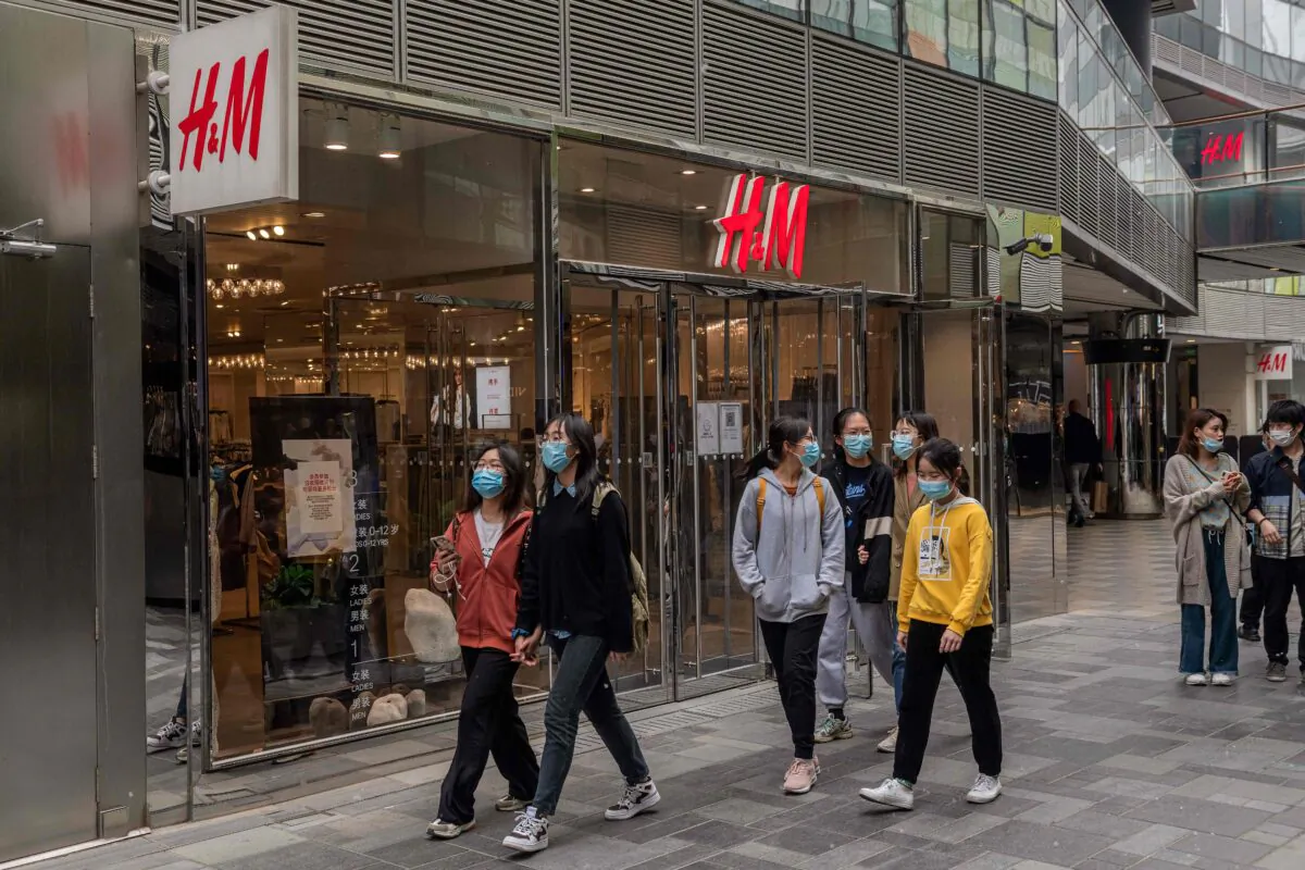 People walk past an H&M store in Beijing on April 5, 2021. (Nicolas Asfouri/AFP)