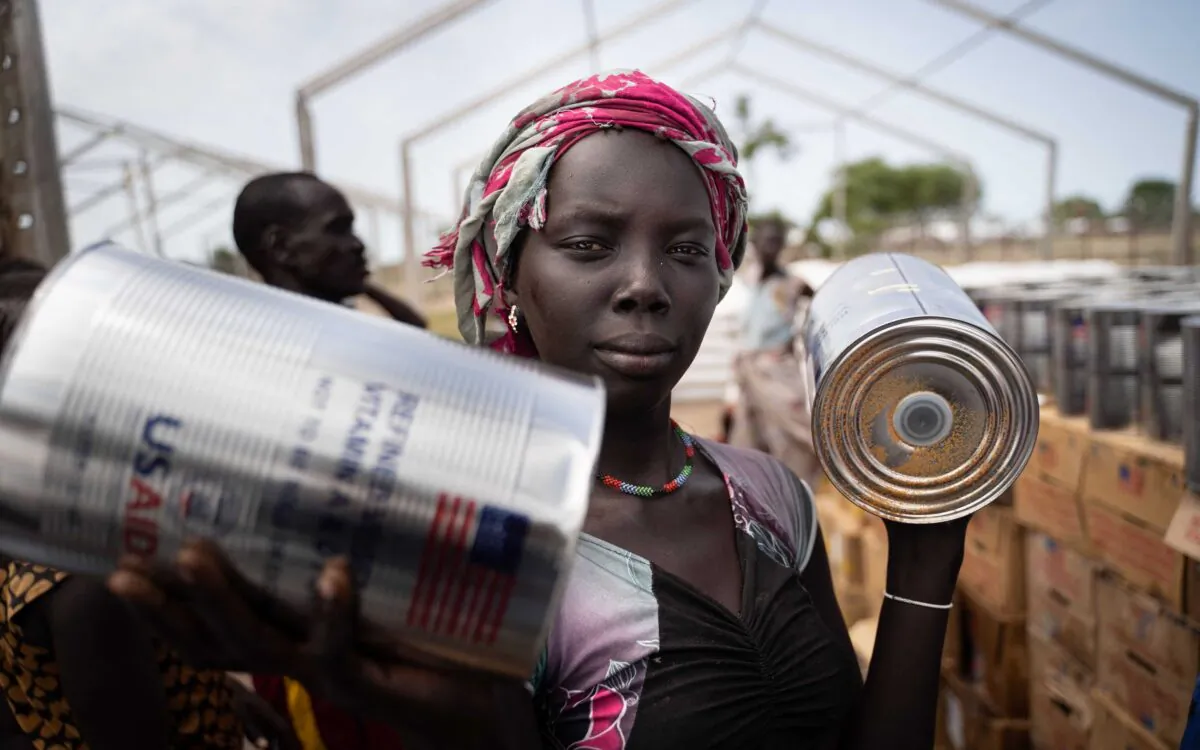 A woman from Murle ethnic group receives cans of oil during a food distribution by United Nations World Food Programme (WFP) in Gumuruk, South Sudan, on June 10, 2021, after her village was recently attacked by an armed youth group. (Simon Wohlfahrt/AFP via Getty Images)