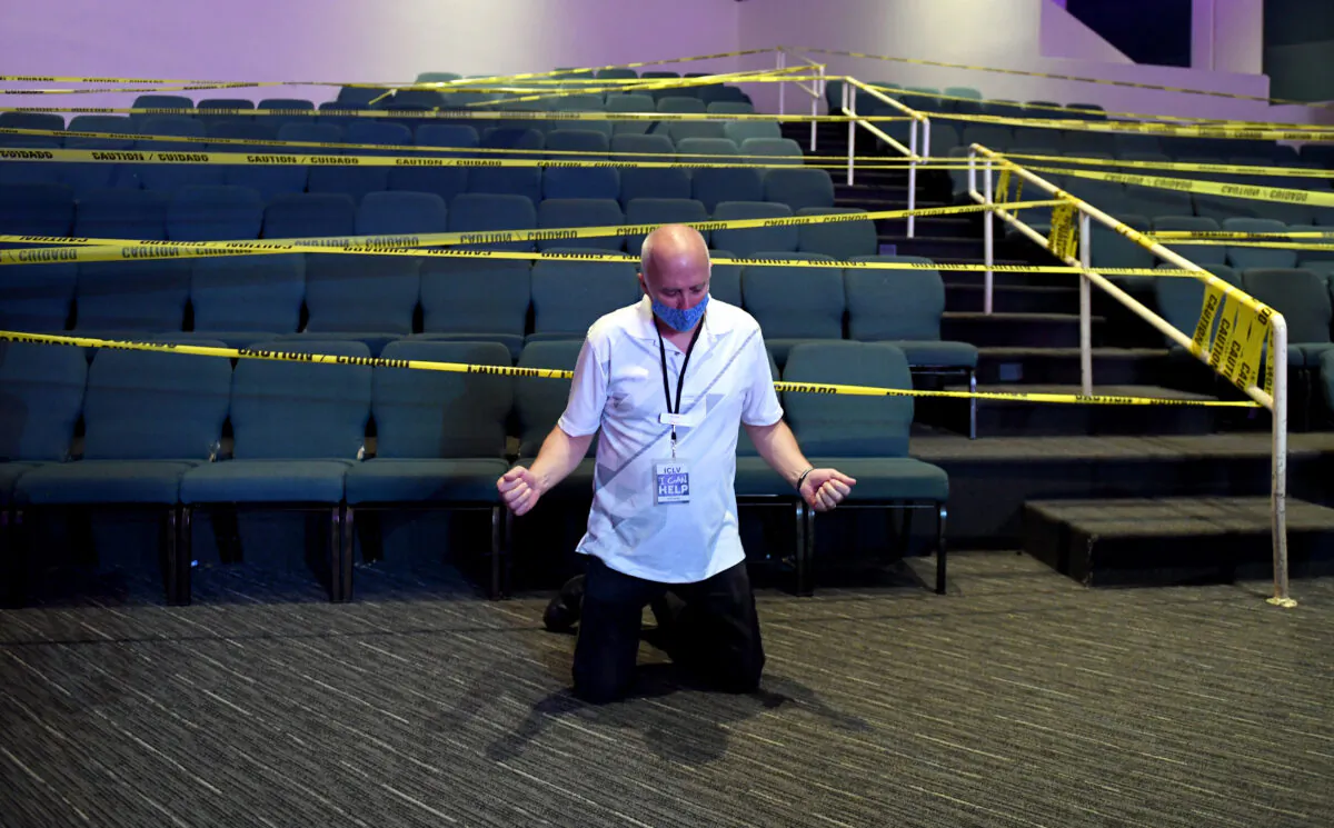 A man kneels to pray in front of seats cordoned off with caution tape due to the CCP virus at the International Church of Las Vegas in Las Vegas, Nev., on May 31, 2020. (Ethan Miller/Getty Images)