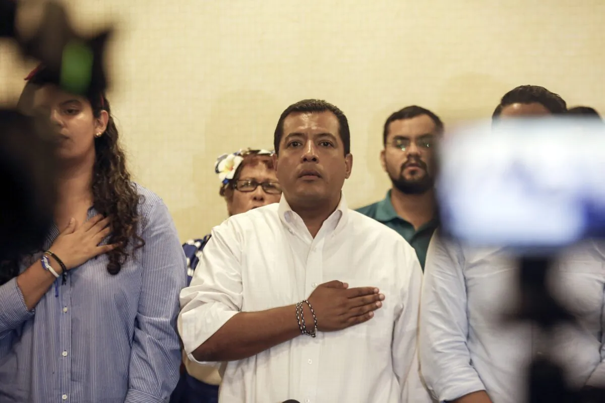 Nicaraguan opposition activist Felix Maradiaga (C) stands at attention as the national anthem is sung during a press conference in Managua, Nicaragua, on Sept. 18, 2019. (Alfredo Zuniga/AP Photo)
