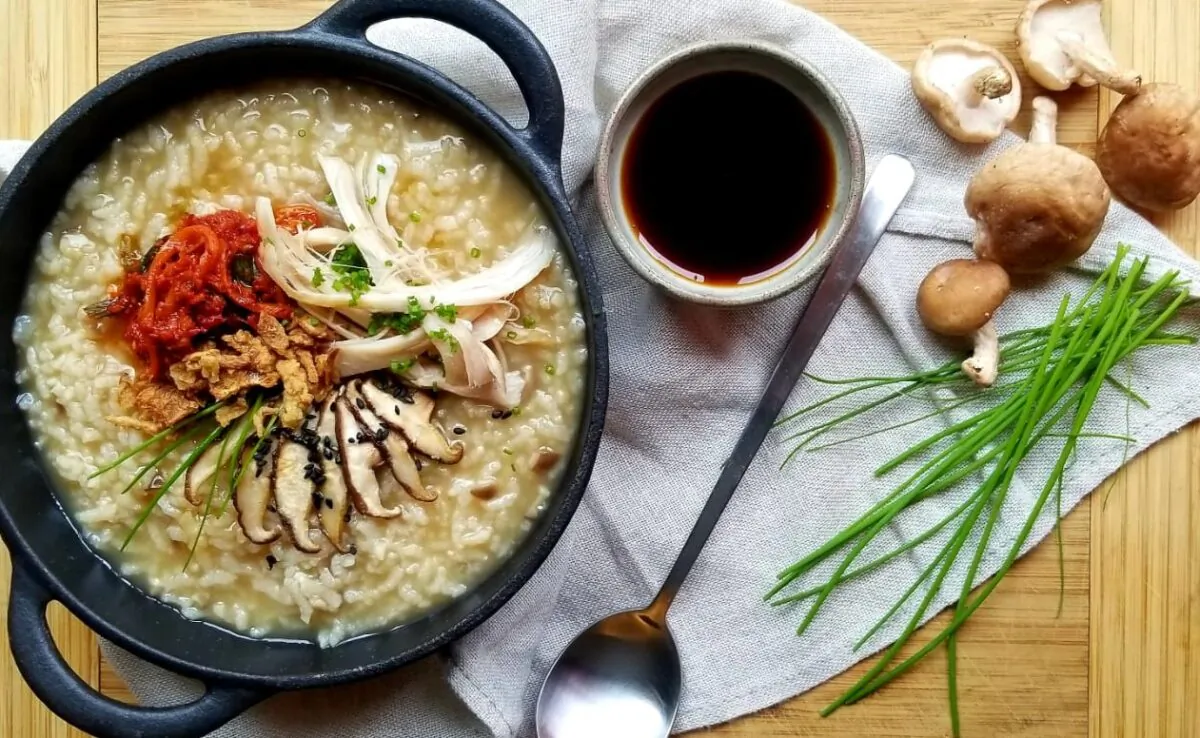 This juk starts with a flavorful homemade chicken stock, and is finished with vibrant toppings including kimchi, pan-fried mushrooms, black sesame seeds, and fresh chives. (Judy Joo)