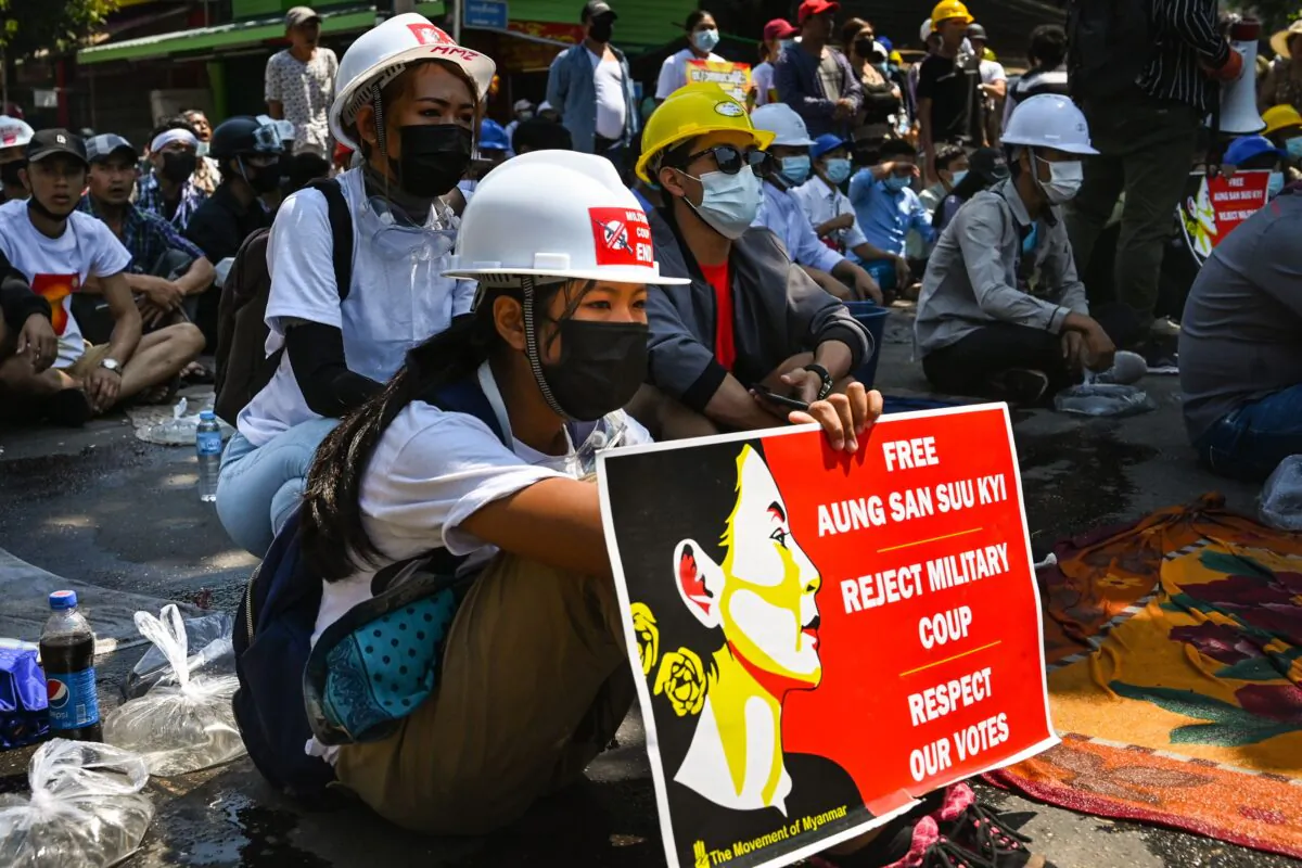 A protester holds a sign with an iamge of detained civilian leader Aung San Suu Kyi as they prepare to face off against security forces during a demonstration against the military coup in Yangon on March 5, 2021. (STR/AFP via Getty Images)