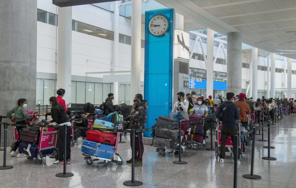 International travellers wait in long lines for transportation to their quarantine hotels at Pearson Airport in Toronto on April 23, 2021. (The Canadian Press/Frank Gunn)