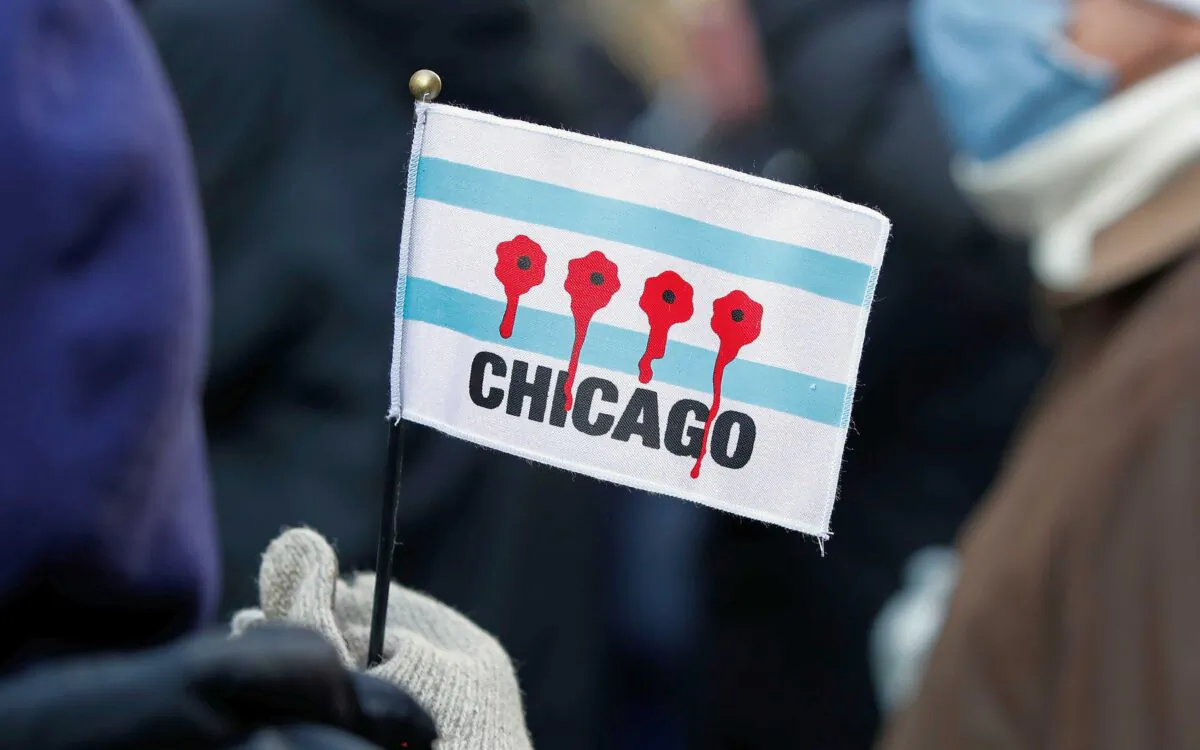 A woman holds a small flag depicting bullet holes with blood during an anti gun violence march on the Magnificent Mile in Chicago, Ill., on Dec. 31, 2020. (Kamil Krzaczynski/AFP via Getty Images)