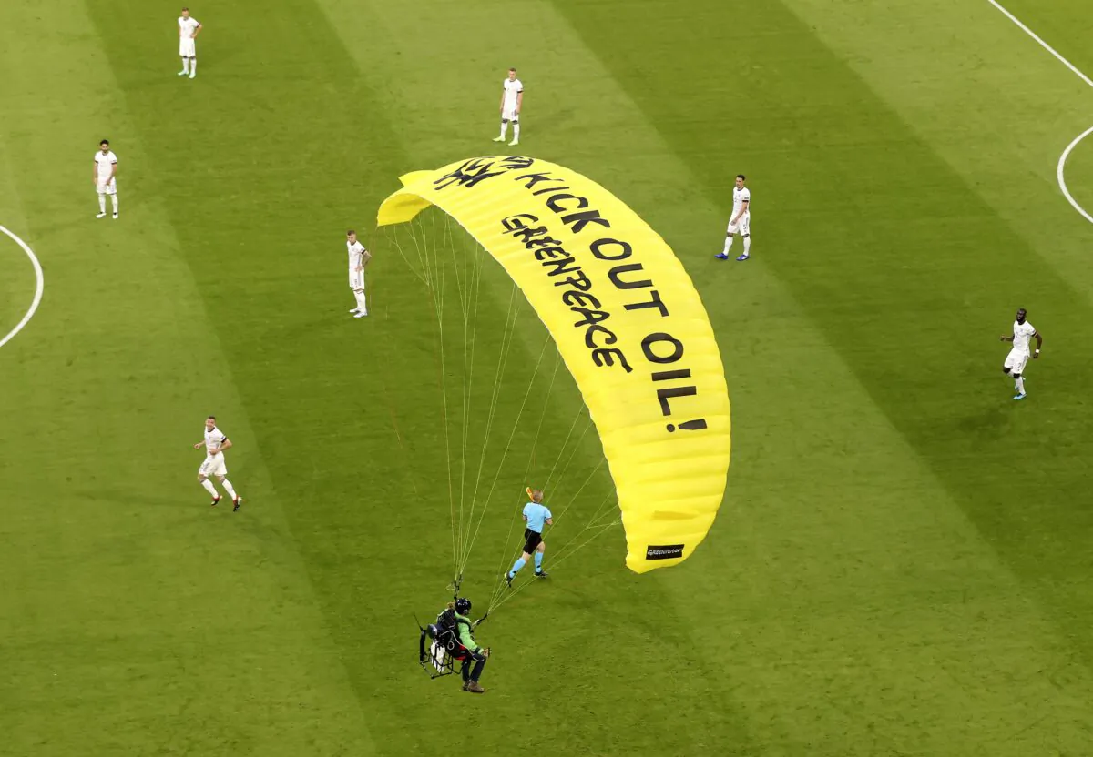 The German players look on as a Greenpeace paraglider lands in the stadium prior to the Euro 2020 soccer championship group F match between France and Germany at the Allianz Arena stadium in Munich, Germany, on June 15, 2021. (ctivist Alexander Hassenstein/Pool via AP)