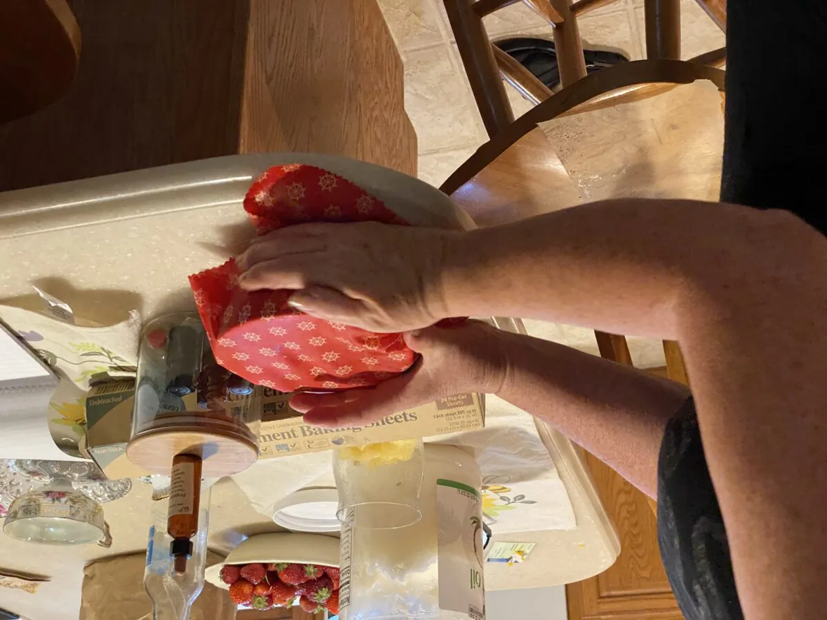 Tressa Hoffman tests a newly made beeswax wrap on a bowl. The warmth of her hands helps mold the beeswax wrap on top of the bowl. (Tamara Browning)