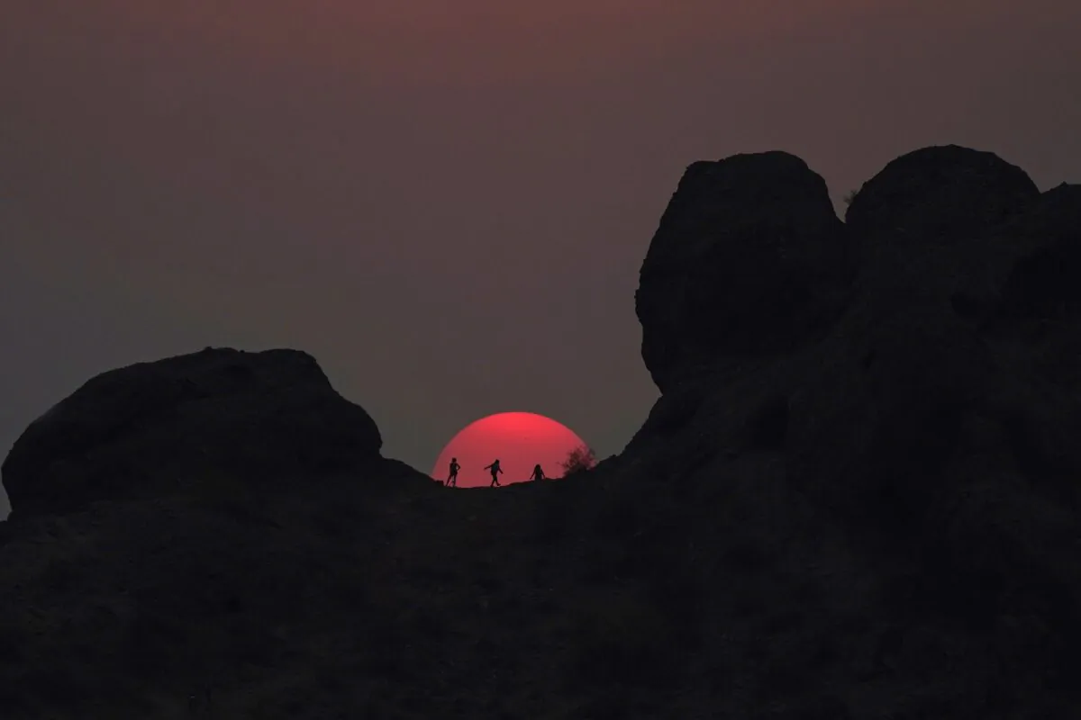 Hikers pause to watch the sunset at Papago Park during a heatwave where temperatures reached 115-degrees, in Phoenix, Arizona, June 15, 2021. (Ross D. Franklin/AP)