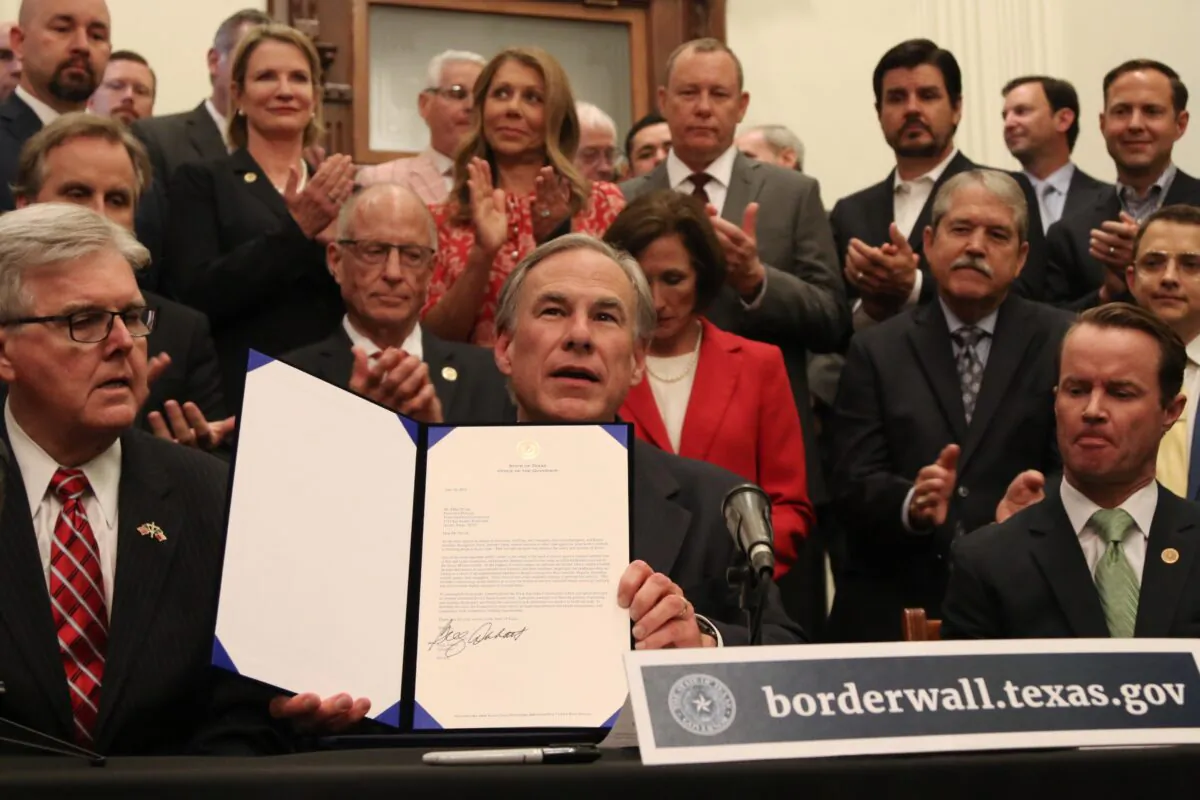 Texas Governor Greg Abbott shows off a bill he signed during a press conference at the state capitol in Austin, Texas, on June 16, 2021. (Mei Zhong/The Epoch Times)