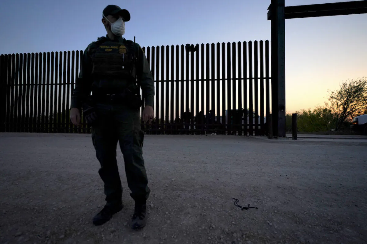 A U.S. border agent looks on near a gate on the U.S.–Mexico border wall, in Abram-Perezville, Texas, in this file photo. (Julio Cortez/AP Photo)