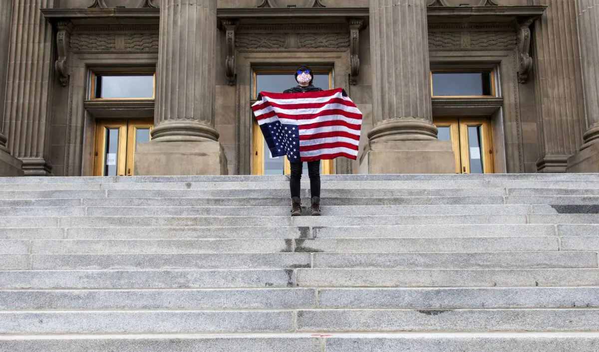 A student holding a U.S. flag upside down stands atop the steps at the Idaho Capitol building in Boise on April 26, 2021. The Idaho Senate has approved legislation aimed at preventing schools and universities from indoctrinating students through teaching critical race theory. (Darin Oswald/Idaho Statesman via AP)