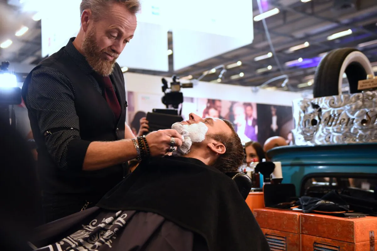 A barber shaves former French Economy Minister and founder of the political movement "En Marche" (On the Move), now president of France, Emmanuel Macron during a visit to the International Hairdressing Show (Salon International de la Coiffure) in Paris on Sept. 12, 2016.  (Eric Feferberg/AFP via Getty Images)