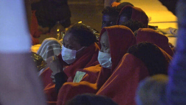 Migrants sit after being rescued