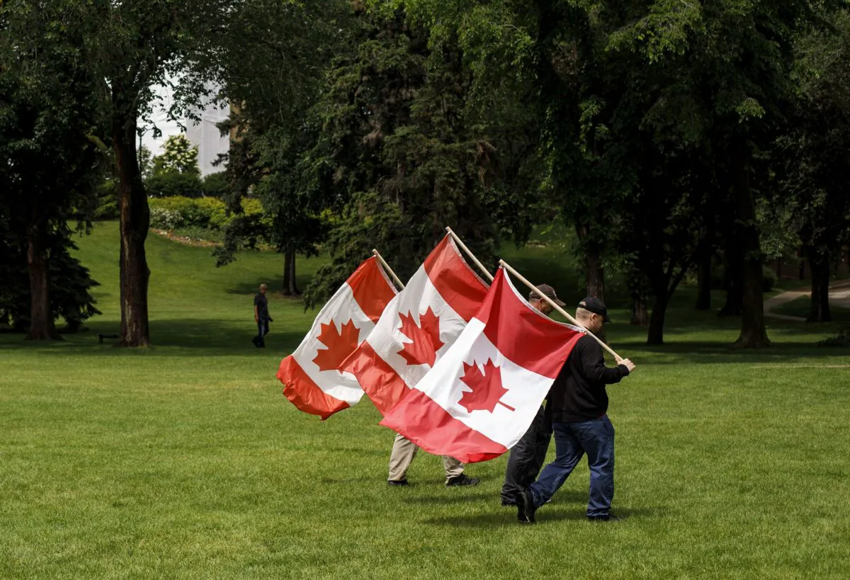 People carry Canadian flags through a park in Edmonton on July 1, 2020. (The Canadian Press/Jason Franson)