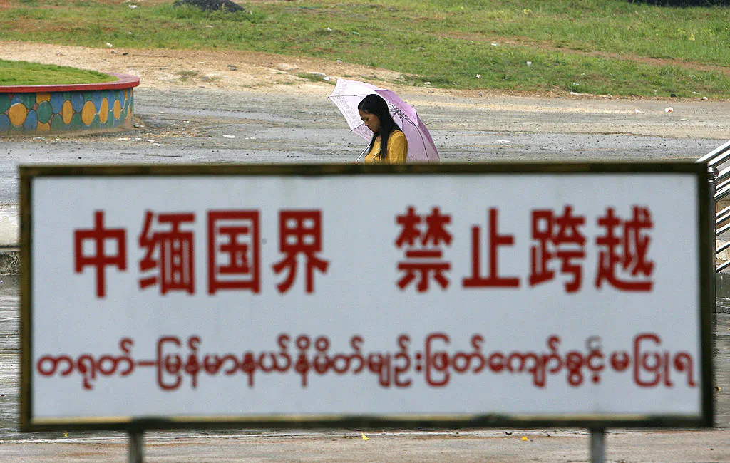 A Burmese woman walks behind a warning sign along the boundary line in the China-Burma border town of Wanding, in China's southwestern province of Yunnan, on Sept. 27 2007. (STR/AFP via Getty Images)