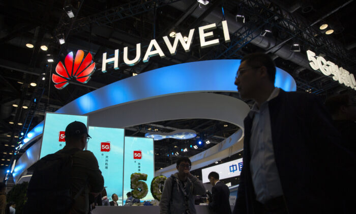 Attendees walk past a display for 5G services from Chinese technology firm Huawei at the PT Expo in Beijing, China, on Oct. 31, 2019. (Mark Schiefelbein/AP Photo)