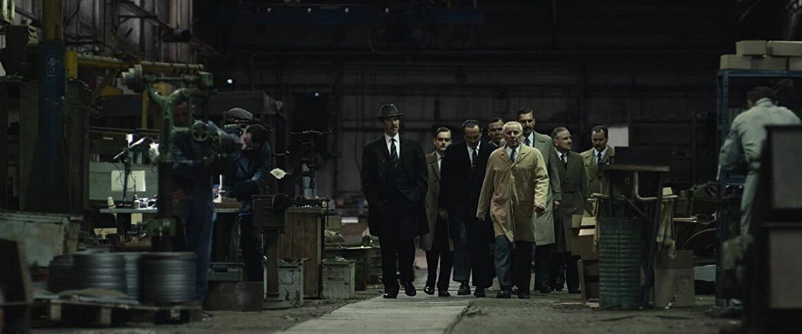 a group of businessmen tour a factory in The Courier