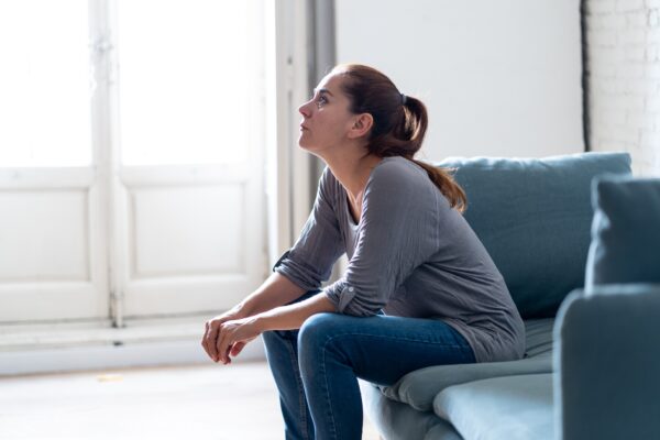 A woman with a sad expression seated on a couch