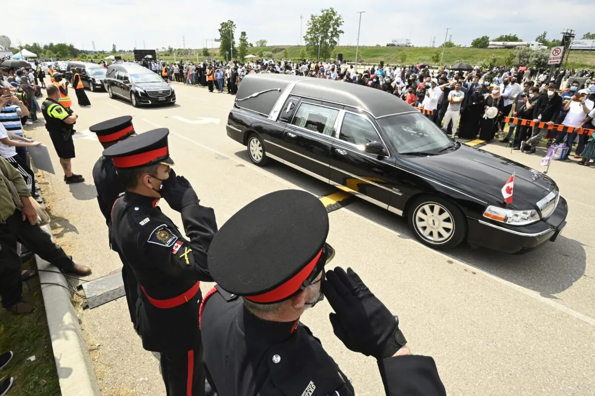 Police officers salute as hearses pass during the funeral for four Muslim family members killed in a deadly vehicle attack, in London, Ont., on June 12, 2021. (Frank Gunn/The Canadian Press)