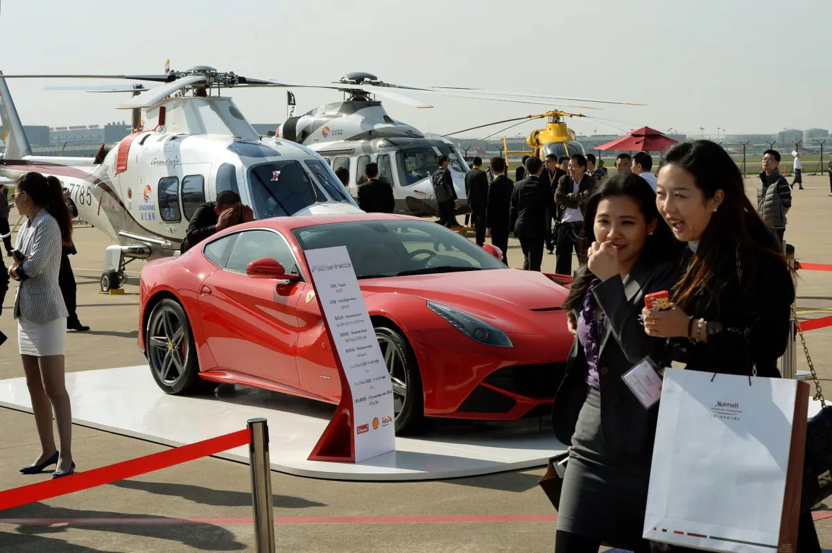 People walk past a Ferrari and helicopters during the Asian Business Aviation Conference and Exhibition at the Shanghai Hongqiao International Airport on April 14, 2014. (Mark Ralston/AFP via Getty Images)