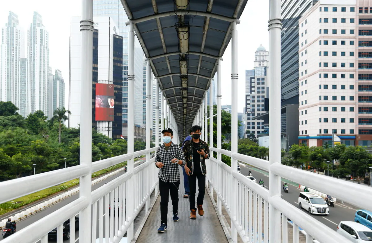 People wearing protective face masks walk on a bridge, amid the coronavirus disease (COVID-19) pandemic, in Jakarta, Indonesia, on June 17, 2021. (Ajeng Dinar Ulfiana/Reuters)