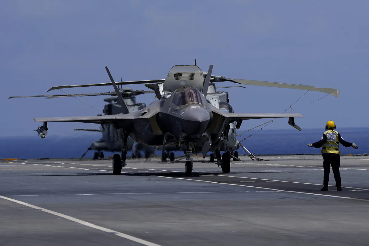 A crew member makes a signal to F-35 aircraft for take off on the UK's aircraft carrier HMS Queen Elizabeth in the Mediterranean Sea on Sunday, June 20, 2021. (Petros Karadjias/AP Photo)